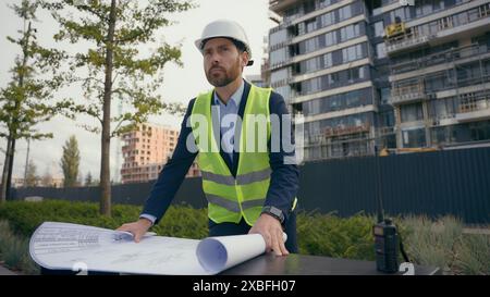 Urban city development business Caucasian man guy male businessman builder engineer in safety hat hard hat looking plan architect civil foreman Stock Photo