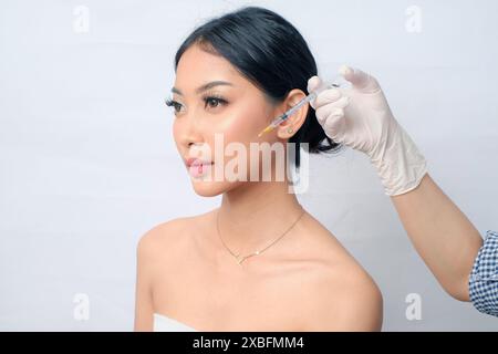 Elegant Asian Woman with Hair in a Bun Receiving Botox Injection for Anti-Aging Treatment Stock Photo