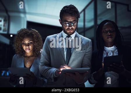Business people, tablet and night for teamwork, planning or research in office with results at tech company. Professional programmer or developer Stock Photo