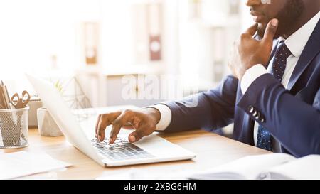 Cropped image of black man in suit working with laptop Stock Photo