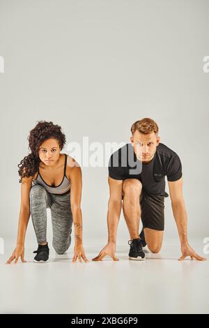 A young interracial sport couple wearing active wear demonstrating perfect squat form in unison on a white background. Stock Photo
