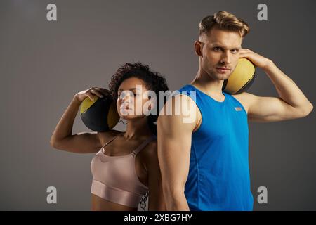 Young multicultural couple in active wear pose with balls in studio setting. Stock Photo