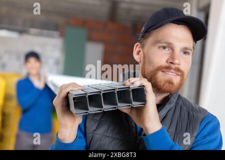 smiling construction worker carrying a metal bar Stock Photo