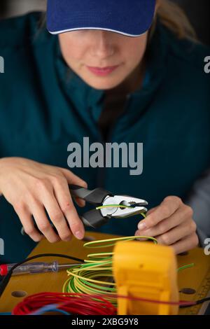 young female maintenance engineer testing voltage with digital multimeter Stock Photo