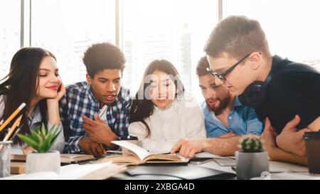 Group of People Sitting Around a Table Looking at Book Stock Photo