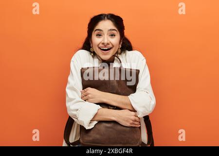 Young indian woman happily holding a brown backpack. Stock Photo