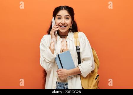Young indian woman holding backpack, talking on phone confidently. Stock Photo