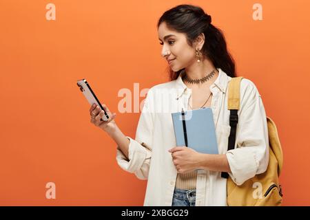 Young indian woman holding backpack, checking phone. Stock Photo