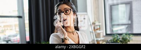 A stylish indian woman in glasses converses on her phone. Stock Photo