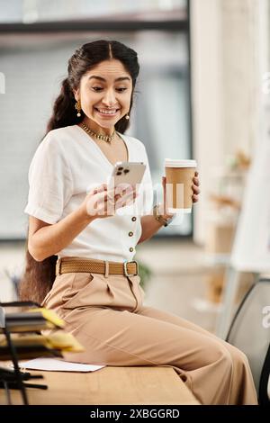 indian woman with coffee and phone at desk. Stock Photo