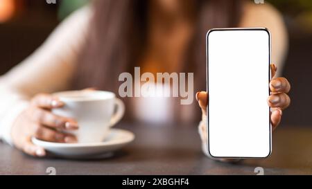 Girl Holding White Smartphone and Drinking Coffee in Cozy Cafe Stock Photo
