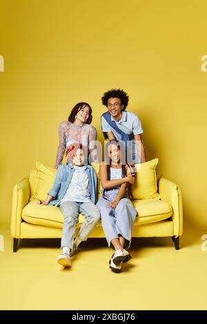 Multicultural friends relax on a bright yellow couch in a stylish studio setting. Stock Photo
