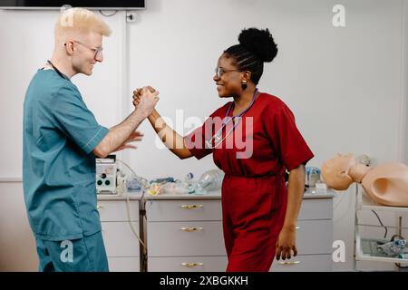 Two medical professionals in scrubs give each other a high five in a hospital room. Stock Photo