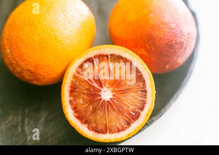 Red or blood oranges on a black plate. Close-up. Selected focus. The concept of vitamins on the table. High quality photo Stock Photo
