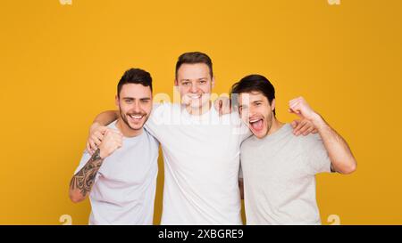 Three happy young men smiling on yellow Stock Photo