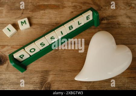 close-up square wooden alphabet blocks, word impossible turns into word possible on vintage background, self-identification, concept self-motivation a Stock Photo