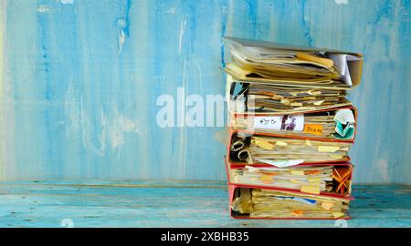 messy file folders,red tape, bureaucracy,overworked,beat the clock business concept,isolated on grungy blue backgound Stock Photo