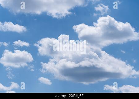 Cumulus clouds are illuminated by the bright sun on a blue sky background Stock Photo