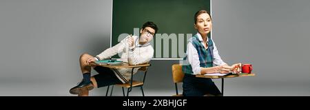 Two elegant students sit at a desk in a college classroom, engaging with a green board. Stock Photo