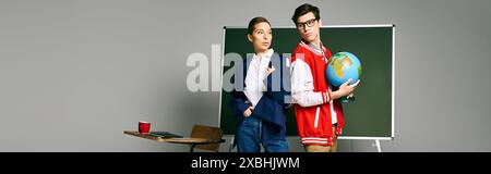 Two students standing in front of a green board in a classroom setting. Stock Photo