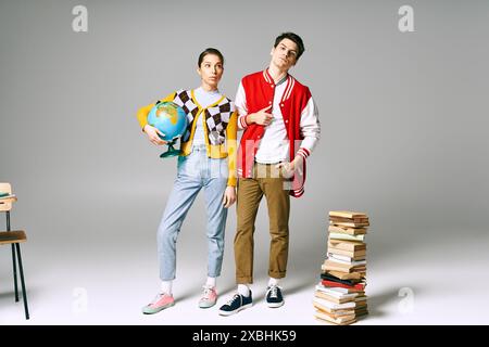 Two young students posing in front of a tall stack of books in a classroom setting. Stock Photo