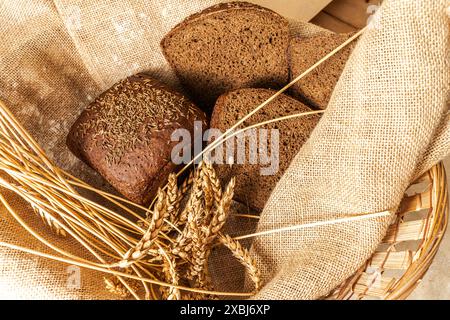 Borodino rye bread with ears of rye in a basket on canvas fabric. High quality photo Stock Photo