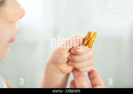 cute cheerful small child, blonde girl 5 years old enjoys crackers in shape letters, learning alphabet fun, happy childhood, Child Nutrition Stock Photo