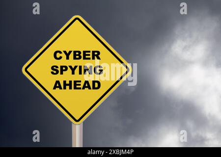 Diamond-shaped crossing sign with yellow background and black border with "Cyber spying ahead" written in the middle. Stock Photo