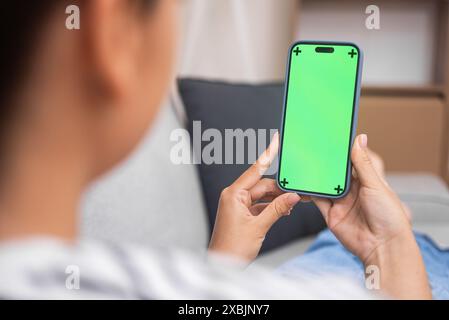 Female student gains new knowledge watching online lessons on mobile phone with chromakey at home Stock Photo