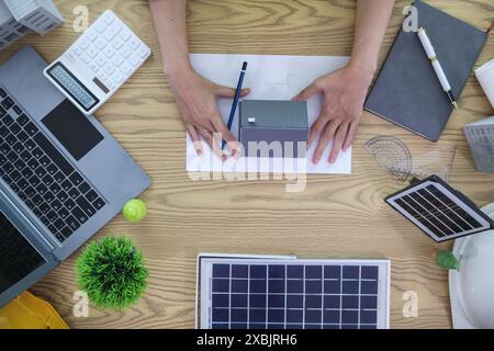 Engineers are reviewing plans from architects to prepare to install solar panels and wind turbines on the building to efficiently produce electricity Stock Photo