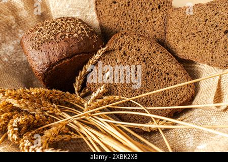 Sliced village rye bread Borodinsky in a wicker basket on canvas fabric with ears of rye. High quality photo Stock Photo