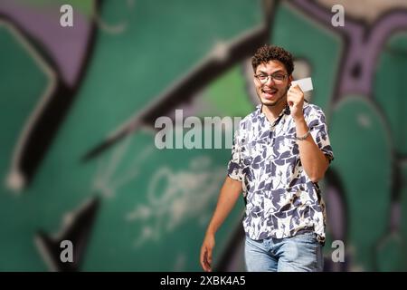 Modern young man with sunglasses shows his credit card in the city. Urban fashion, finance, lifestyle. Stock Photo