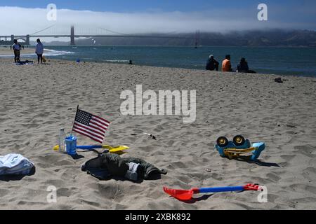 San Francisco, CA - July 25, 2023: American flag waving on the beach near Golden Gate Bridge. Stock Photo