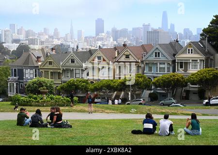 San Francisco, CA, USA - July 27, 2023: People rest near groups of "Painted Ladies" the row of Victorian houses. Stock Photo