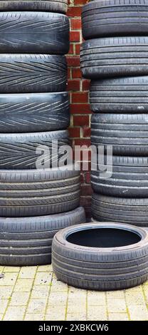 Germany Dortmund Pile of old tires stacked on top of each other, red brick wall in the background. Stock Photo