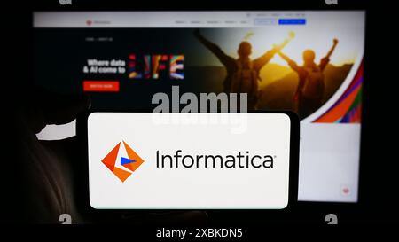Person holding smartphone with logo of US software development company Informatica Inc. in front of website. Focus on phone display. Stock Photo