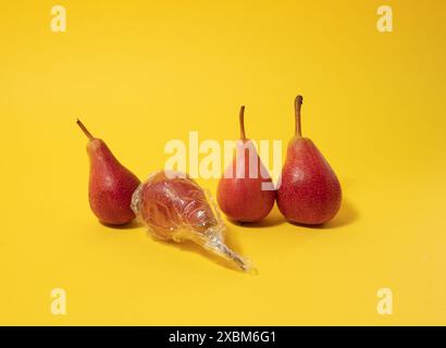 Pears arranged in a horizontal line, one pear in plastic foil. Top view Stock Photo