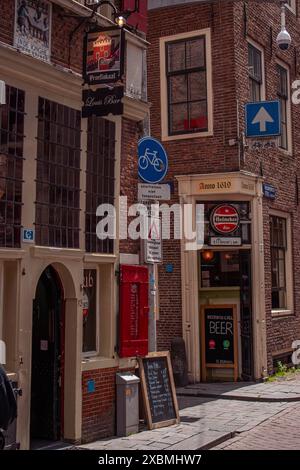 Old town centre with cobblestones, red brick buildings, signs and narrow streets, Amsterdam, Netherlands Stock Photo