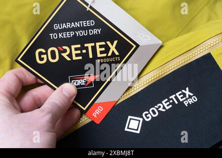 Woman's hand holding a label on hiking trousers advertising Gore Tex material, UK. Gore Tex is made from expanded polytetrafluoroethylene (PTFE) Stock Photo