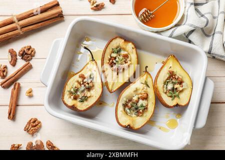 Tasty baked pears with nuts, blue cheese, thyme and honey in baking dish on wooden table, flat lay Stock Photo