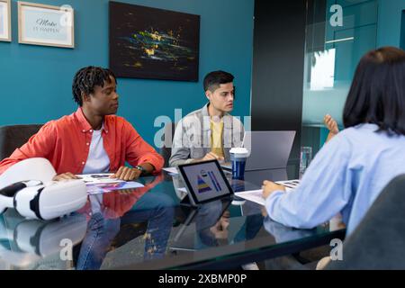 Young team collaborates on laptop and tablet in diverse business startup Stock Photo