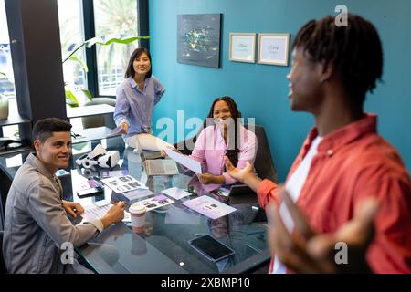 Young diverse colleagues discuss documents in a modern office, focusing on teamwork and business Stock Photo