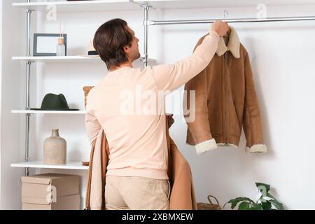 Handsome young man arranging stylish clothes in dressing room Stock Photo