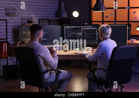 Young programmers working in office at night, back view Stock Photo