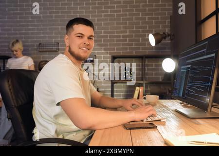 Male programmer working with computer in office at night Stock Photo