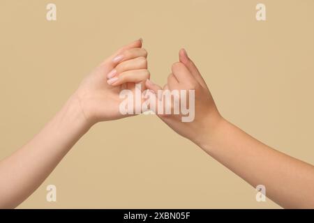 Women making pinky promise on color background, closeup. Friendship Day celebration Stock Photo