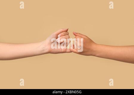 Women making pinky promise on color background, closeup. Friendship Day celebration Stock Photo