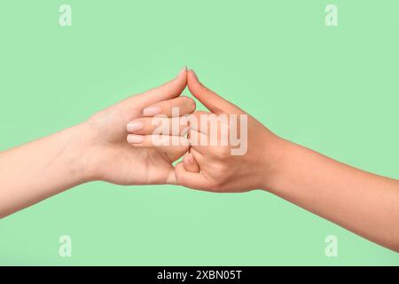 Women making pinky promise on color background, closeup. Friendship Day celebration Stock Photo