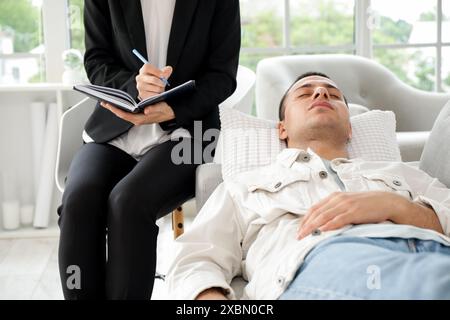 Female psychologist writing on notebook with hypnotized patient in office Stock Photo