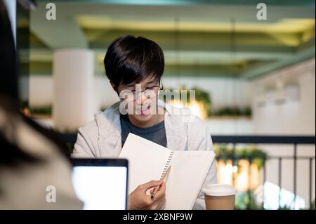 A young, smart Asian male college student is tutoring, helping his friend with math homework, discussing a co-project, or preparing for an exam togeth Stock Photo